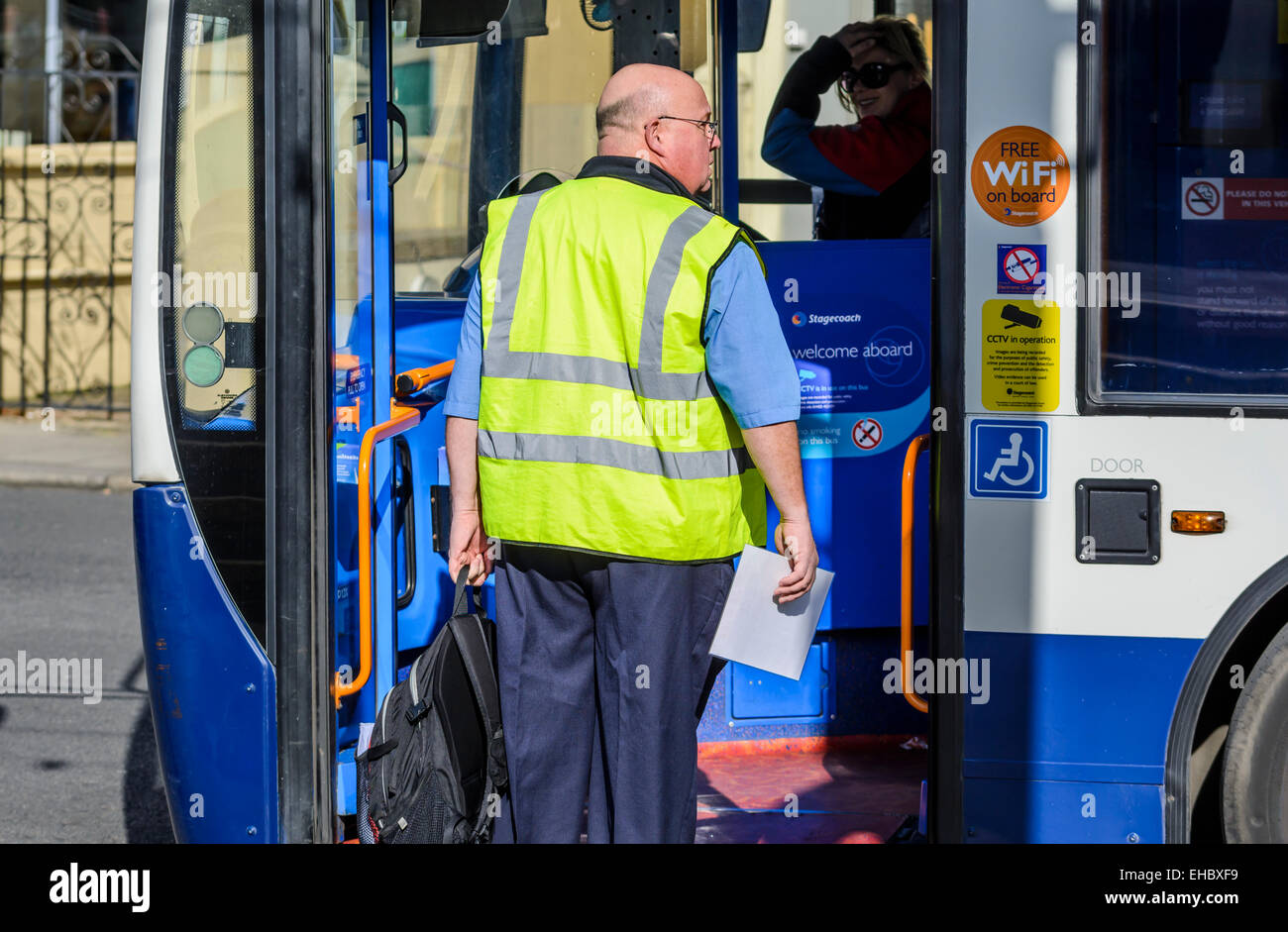 Maschio di conducente di bus di salire a bordo di un autobus Stagecoach a prendere in consegna da un altro driver. Foto Stock