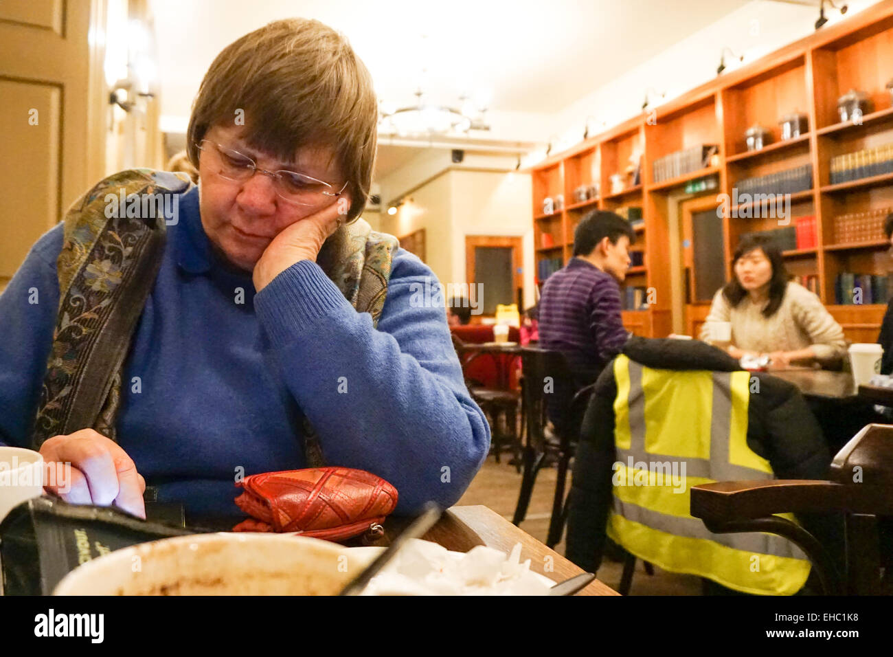 Donna seduta in una caffetteria la lettura Foto Stock