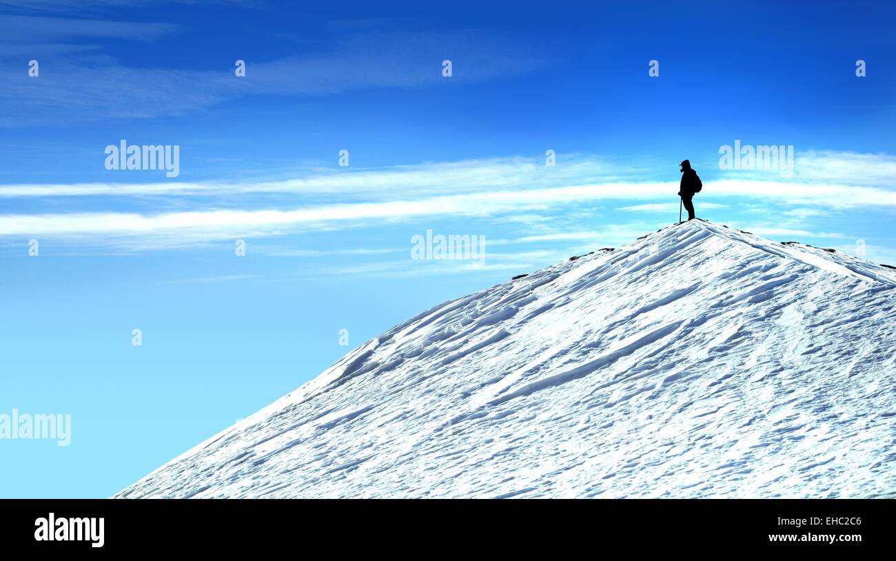 Scalatore sulla cima della montagna a contemplare la natura uomo sulla cima della montagna con la neve e il blu del cielo. Foto Stock