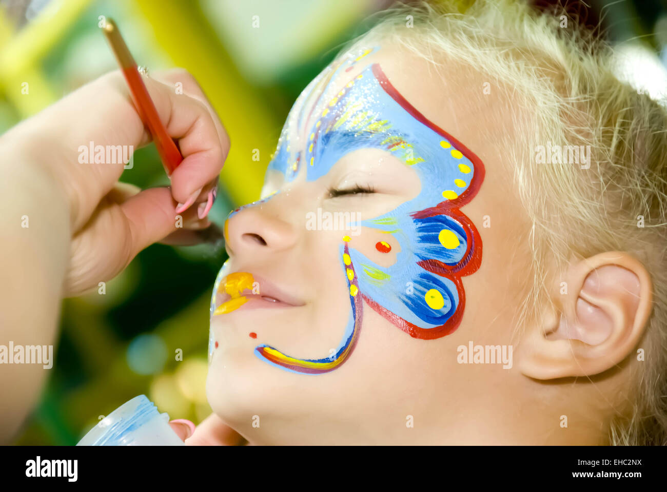 Bellissima ragazza con gli occhi blu con farfalla dipinta sul suo viso Foto Stock