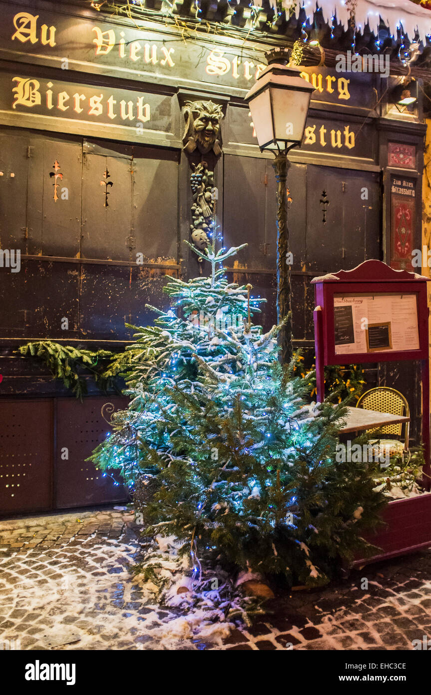 Snowy piccolo albero di Natale davanti a 'Au Vieux Strasbourg' ristorante chiuso di notte sul tempo di Natale Strasburgo Alsace Francia Europa Foto Stock