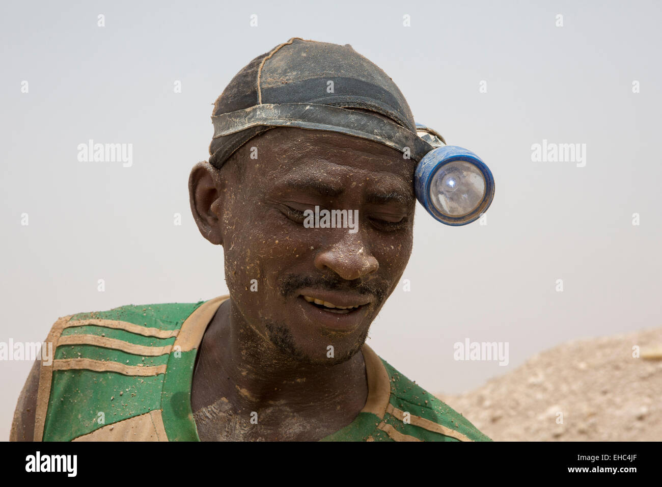 KOMOBANGAU, NIGER, : un minatore che indossa la sua torcia da testa accanto alla verticale di albero di entrata di loro oro grezzo di miniera. Foto Stock