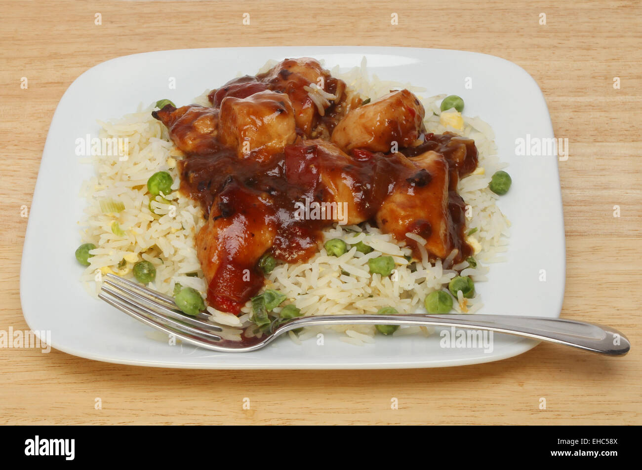 Pasto cinese, pollo in salsa del fagiolo nero con riso su una piastra con una forcella Foto Stock
