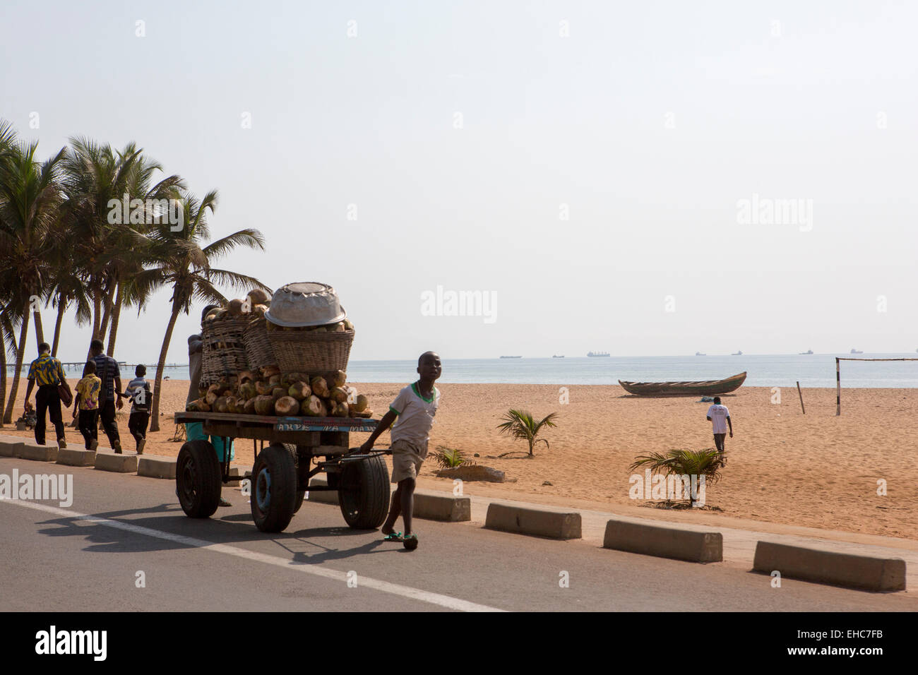 A Lomé, Togo, 9 dicembre 2012; un ragazzo tira un carrello di noci di cocco lungo la strada sulla spiaggia. Foto Stock