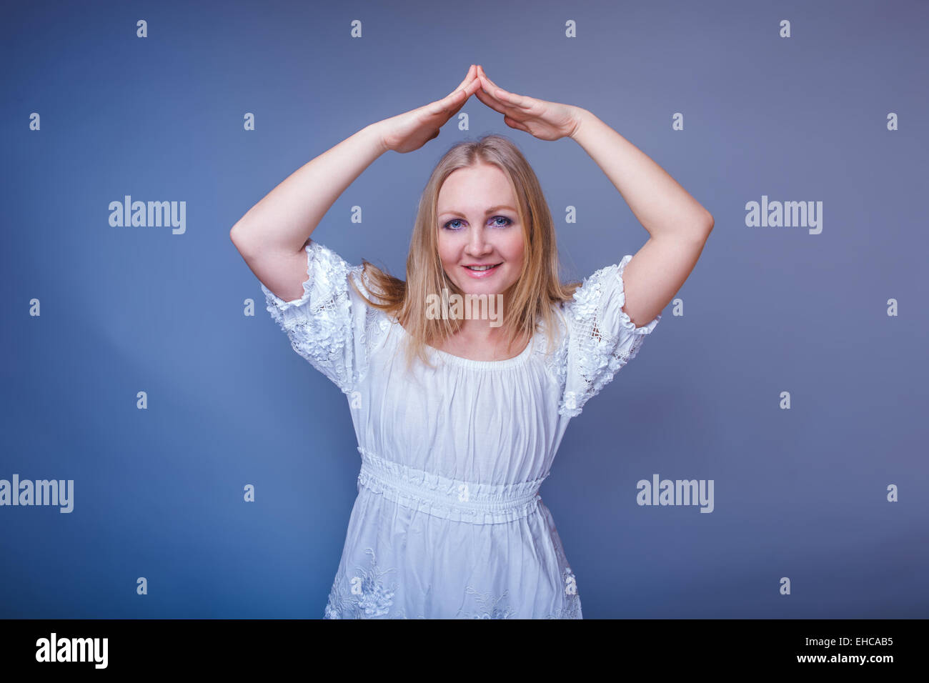 Ragazza bionda aspetto europeo in un abito bianco piegato la sua mano Foto Stock