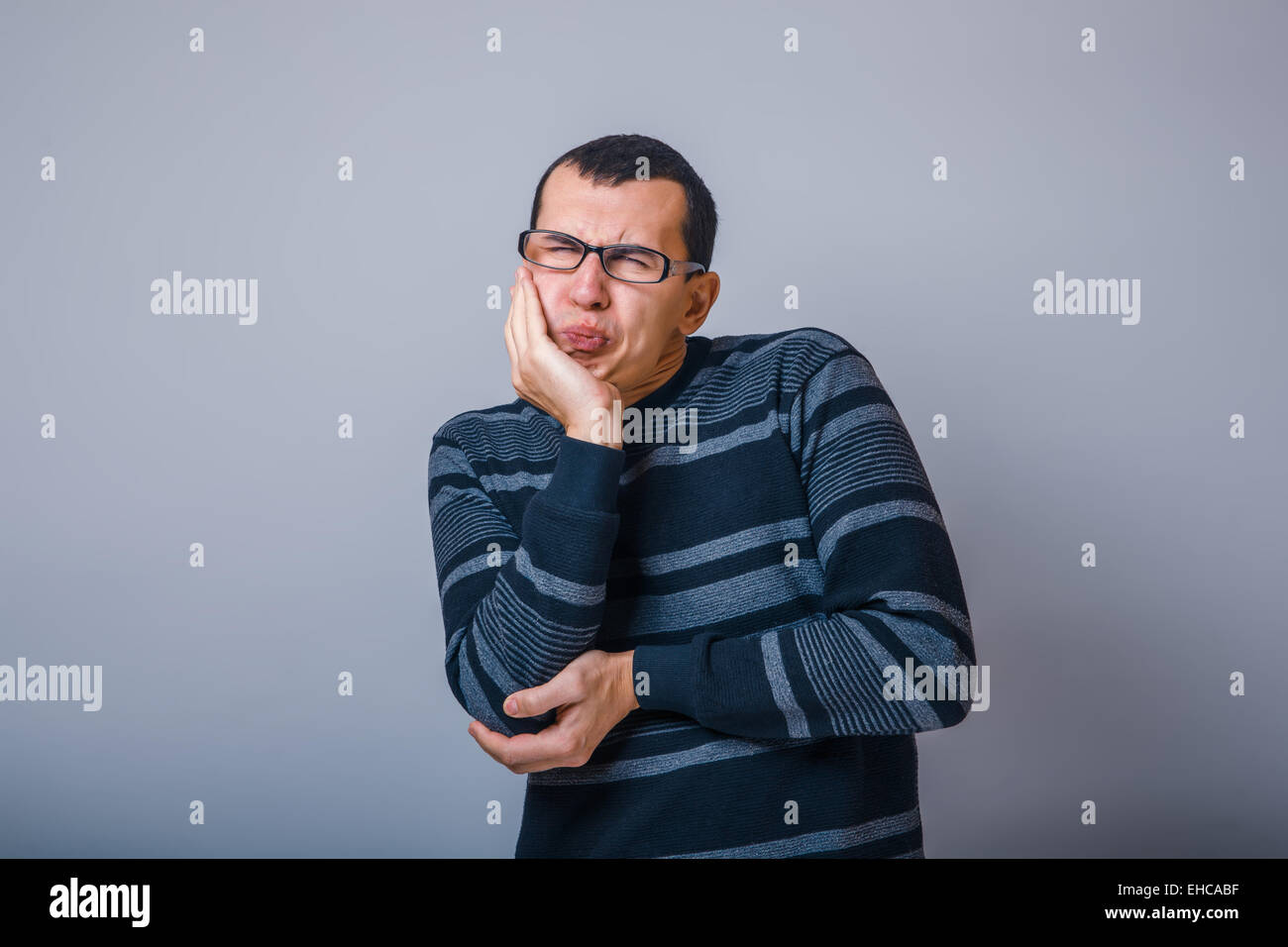 Maschio di aspetto europeo brunet in un maglione a righe di mettere il suo Foto Stock