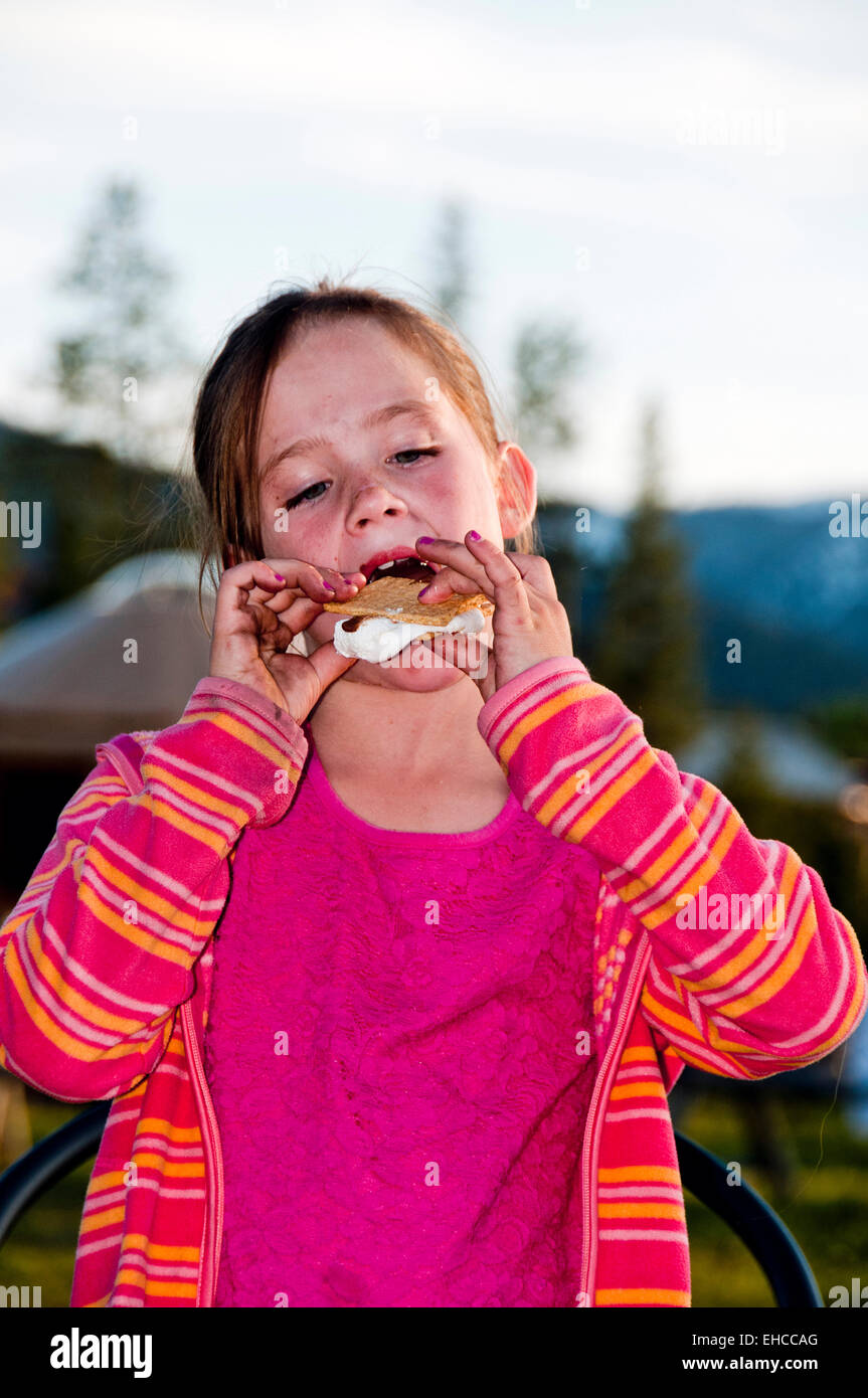 Ragazza giovane mangiare un s'more su un viaggio di campeggio in Idaho (MR) Foto Stock