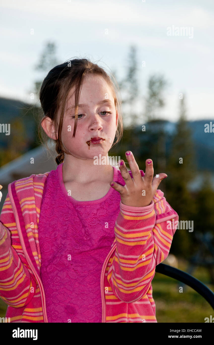 Ragazza giovane leccarsi le dita dopo aver mangiato una s'more (MR) Foto Stock