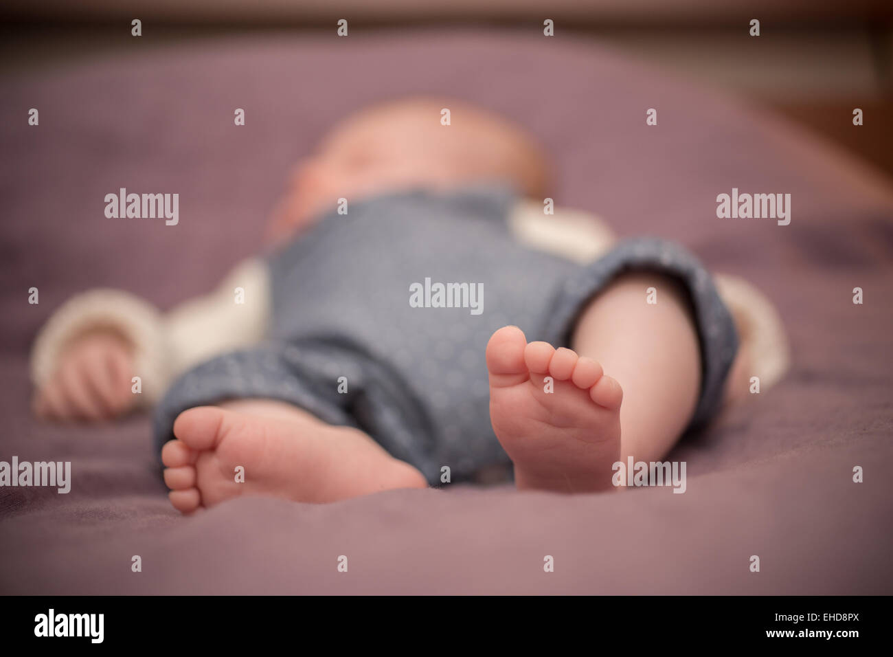 Il bambino dorme a piedi nudi su un letto Foto Stock