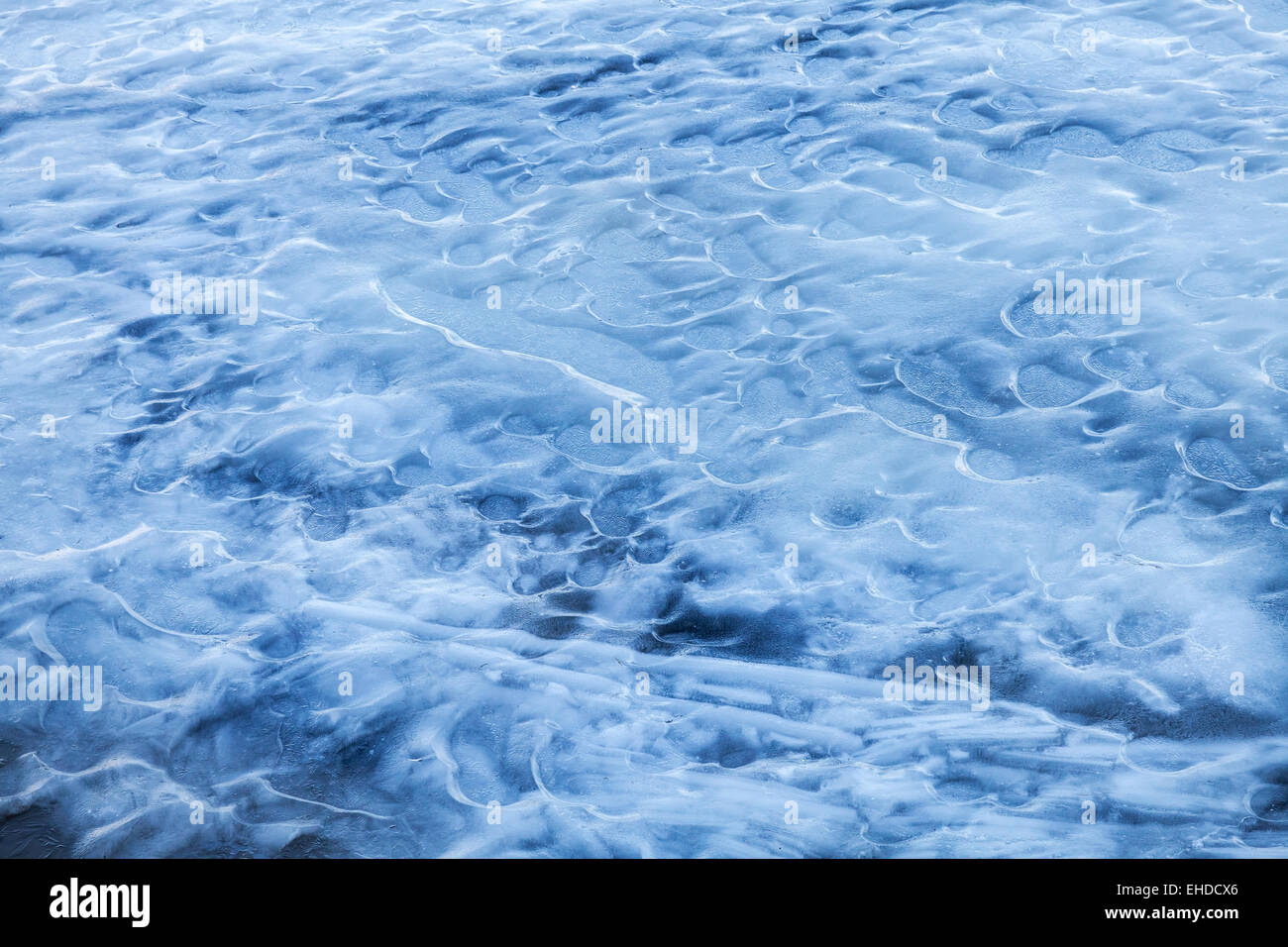 Blu ghiaccio in fusione sulla superficie congelata di acqua di fiume Foto Stock