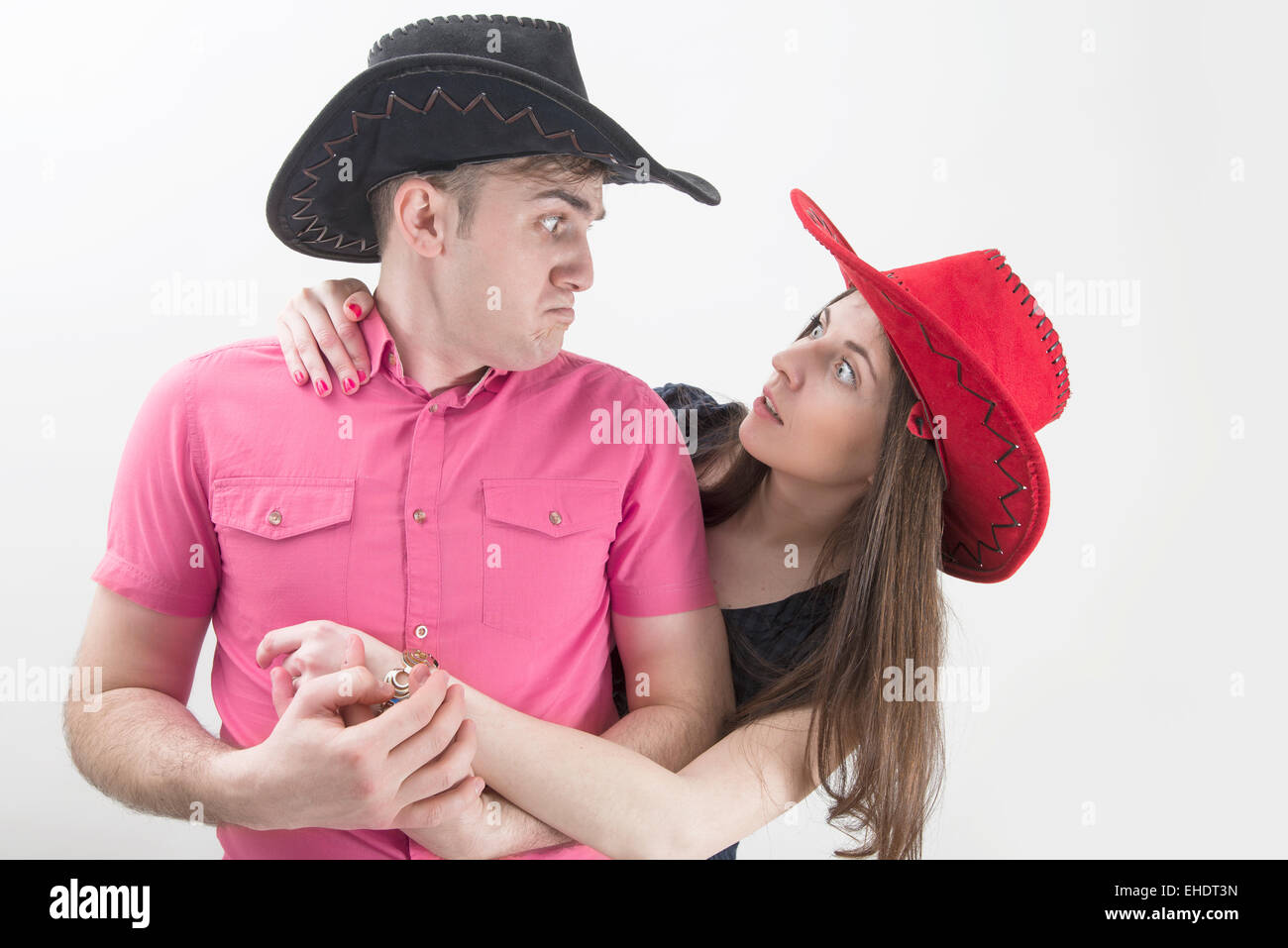 Coppia giovane con cappelli da cowboy rendendo silly volti su sfondo bianco Foto Stock