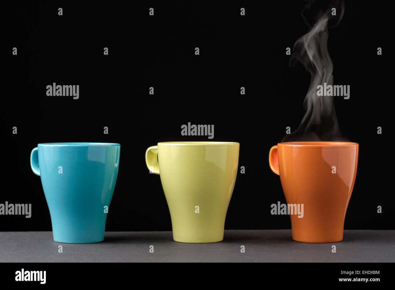 Tre tazza colorata in una fila. Uno con il vapore. Foto Stock Tre tazza colorata in una fila. Uno con il vapore. Foto Stock