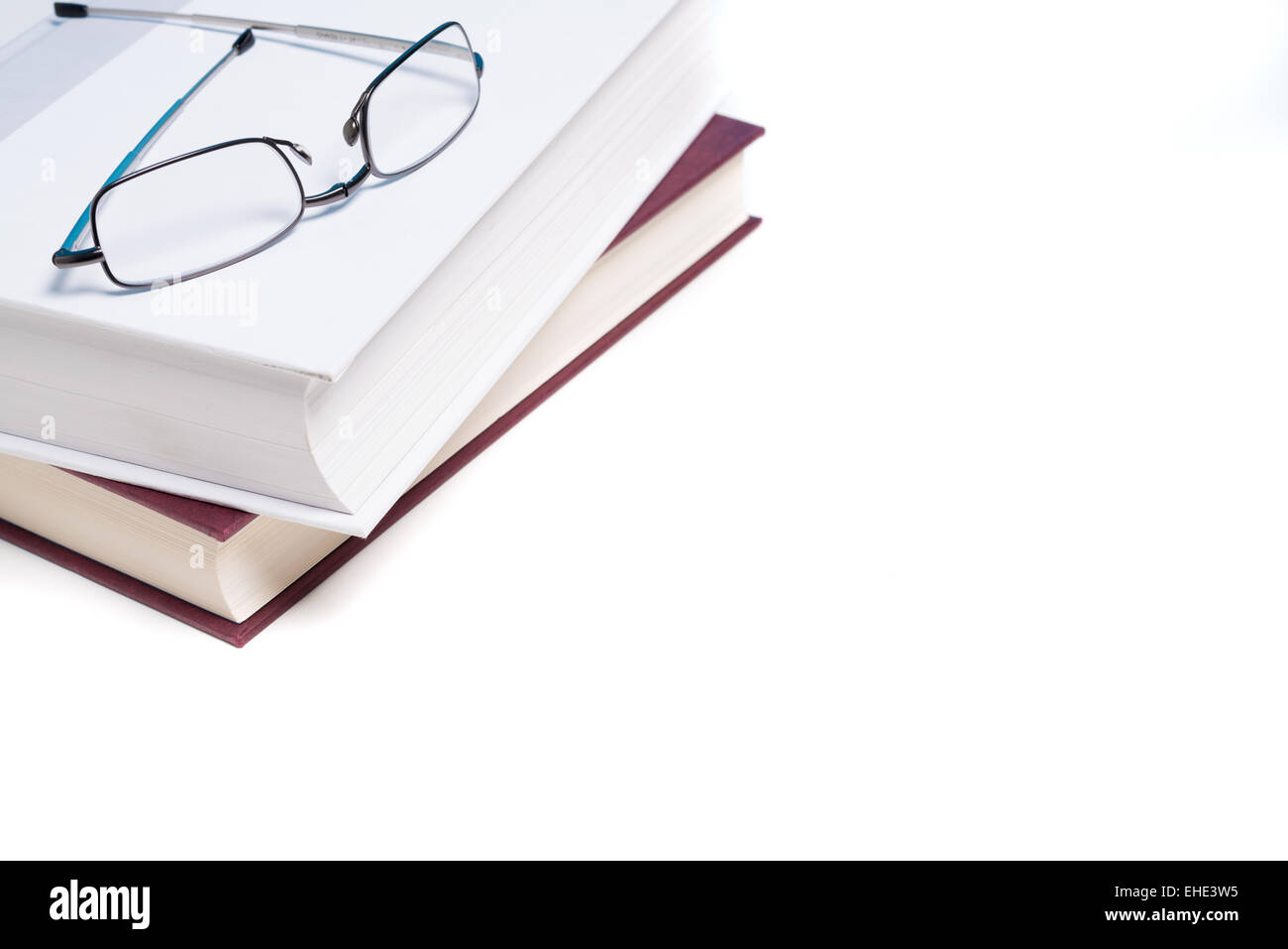 Pila di libri e un paio di occhiali per leggere su sfondo bianco Foto Stock