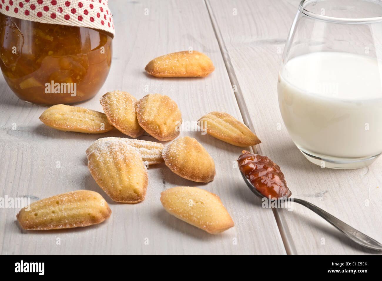 Il francese orange fiore profumato biscotti - madeleines, marmellata di arance e bicchiere di latte Foto Stock