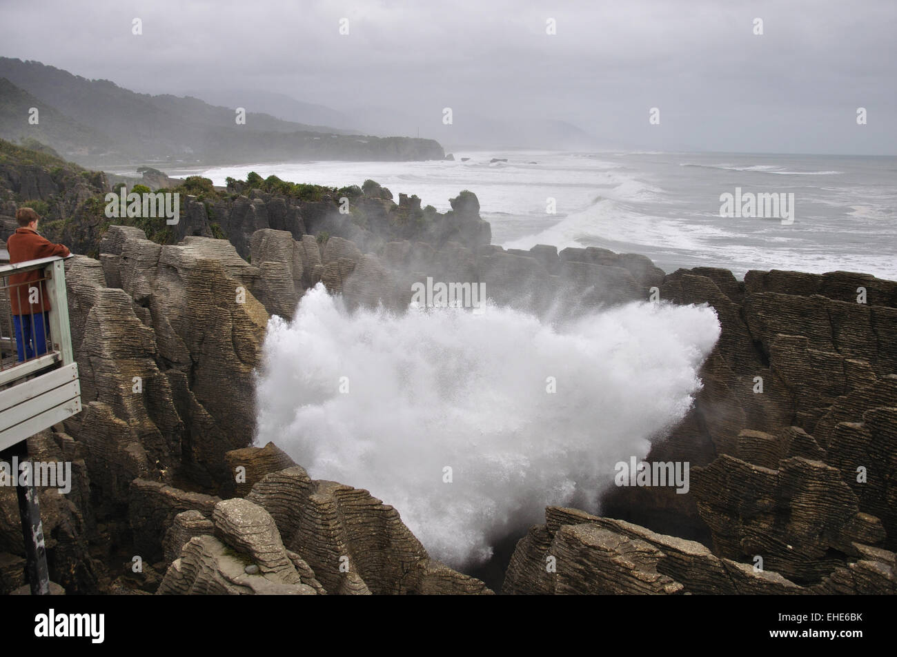 Il turista a godere il principale foro di sfiato in azione a Pancake Rocks, Punakaiki, nella costa occidentale dell'Isola del Sud, Nuova Zelanda Foto Stock