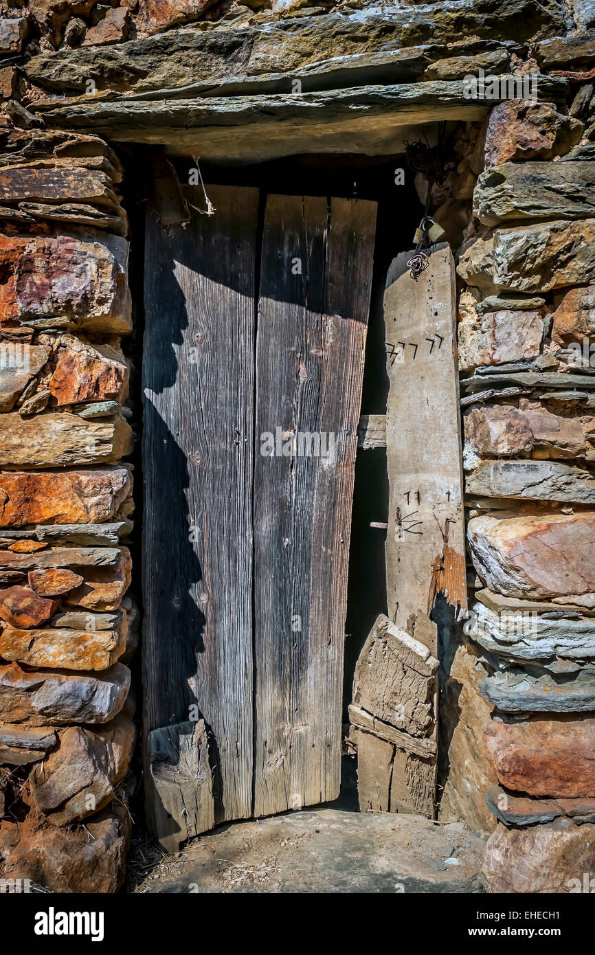 La porta di legno e muro di pietra di una vecchia casa Foto Stock