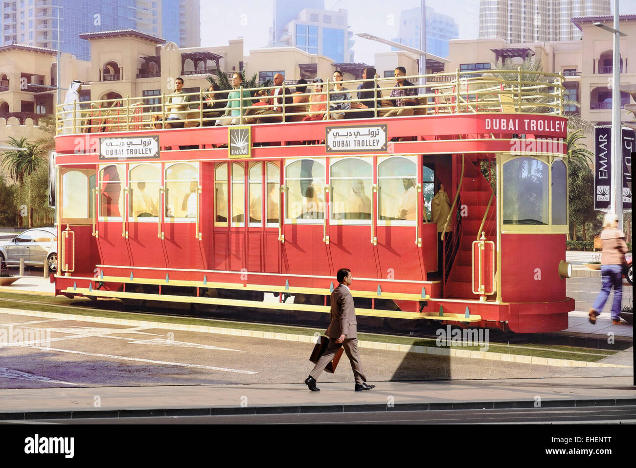 L'uomo cammina passato grandi cartelloni pubblicitari il nuovo Dubai carrello - una cella a combustibile idrogeno alimentato turistico tram in Dubai Regno Ara Foto Stock