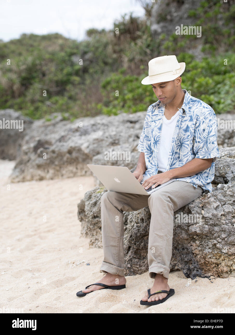 Uomo con Macbook Air di Apple computer portatile laptop al lavoro sulla spiaggia mentre è in vacanza Foto Stock