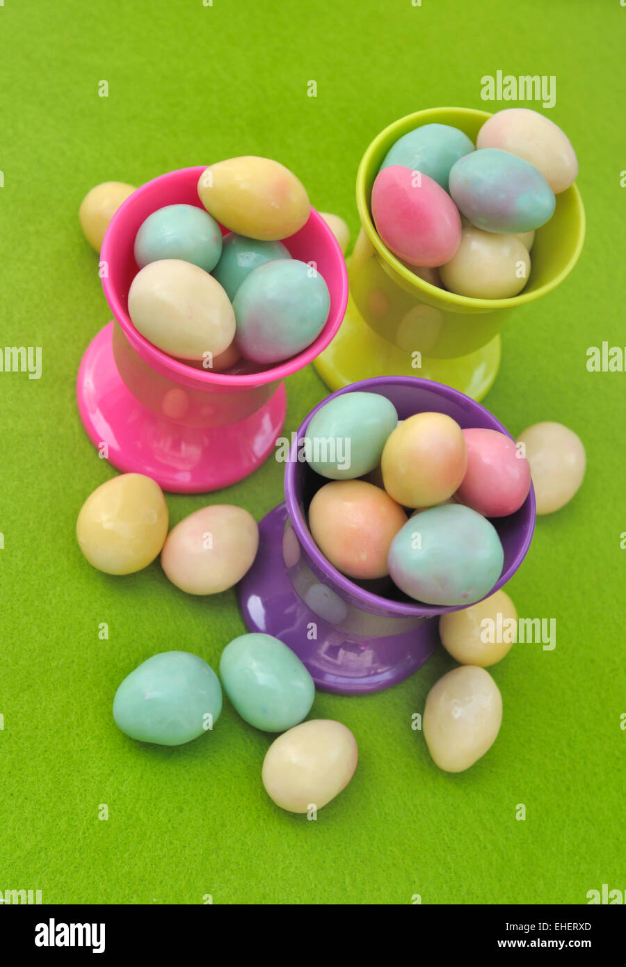 Uovo tazze riempite con piccole uova di Pasqua su sfondo verde Foto Stock
