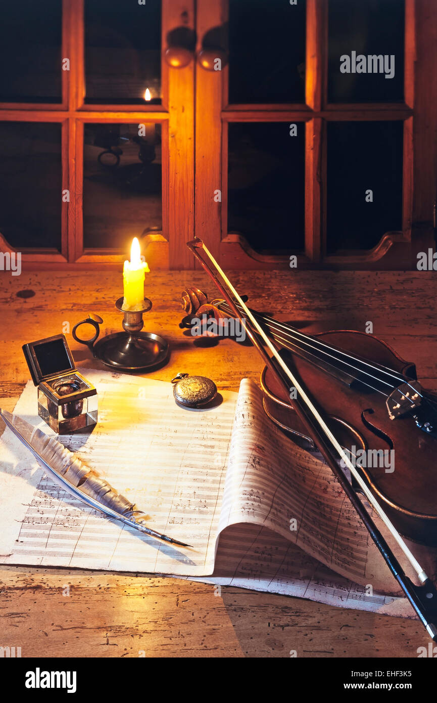 Violino su di un foglio di musica con inkwell e quill, illuminata da una candela Foto Stock