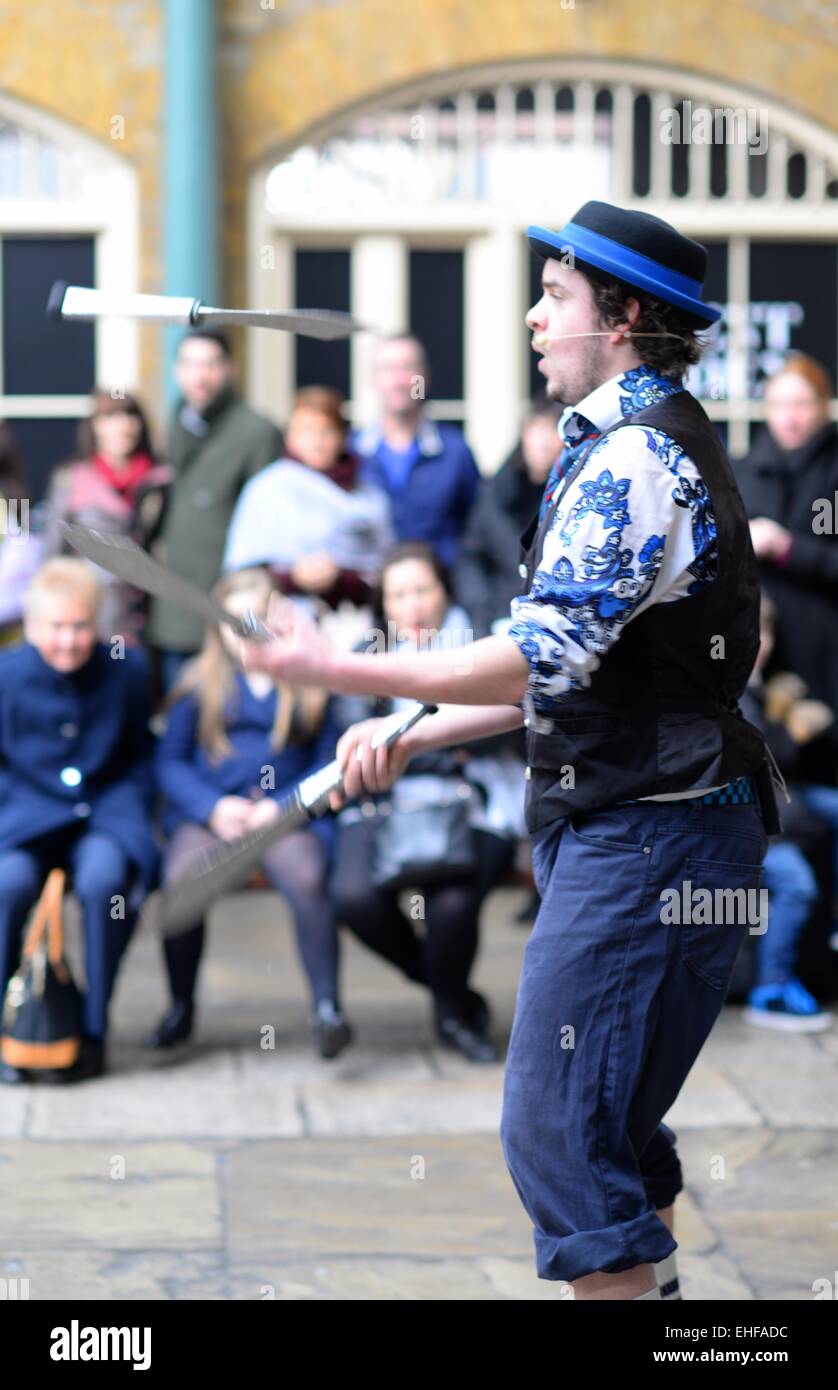 Giocoliere, giocoleria con coltelli per una folla nel mercato indoor di Covent Garden, Londra, Regno Unito Foto Stock