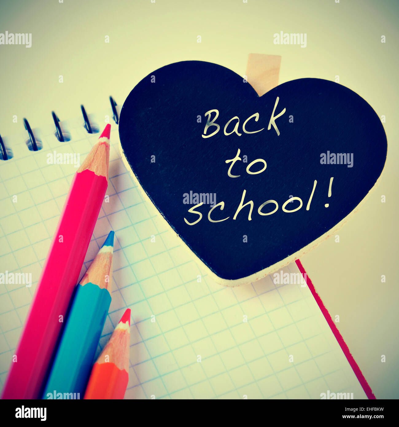 Frase torna a scuola scritto in una a forma di cuore blackboard e alcune matite di diversi colori su un notebook con un r Foto Stock
