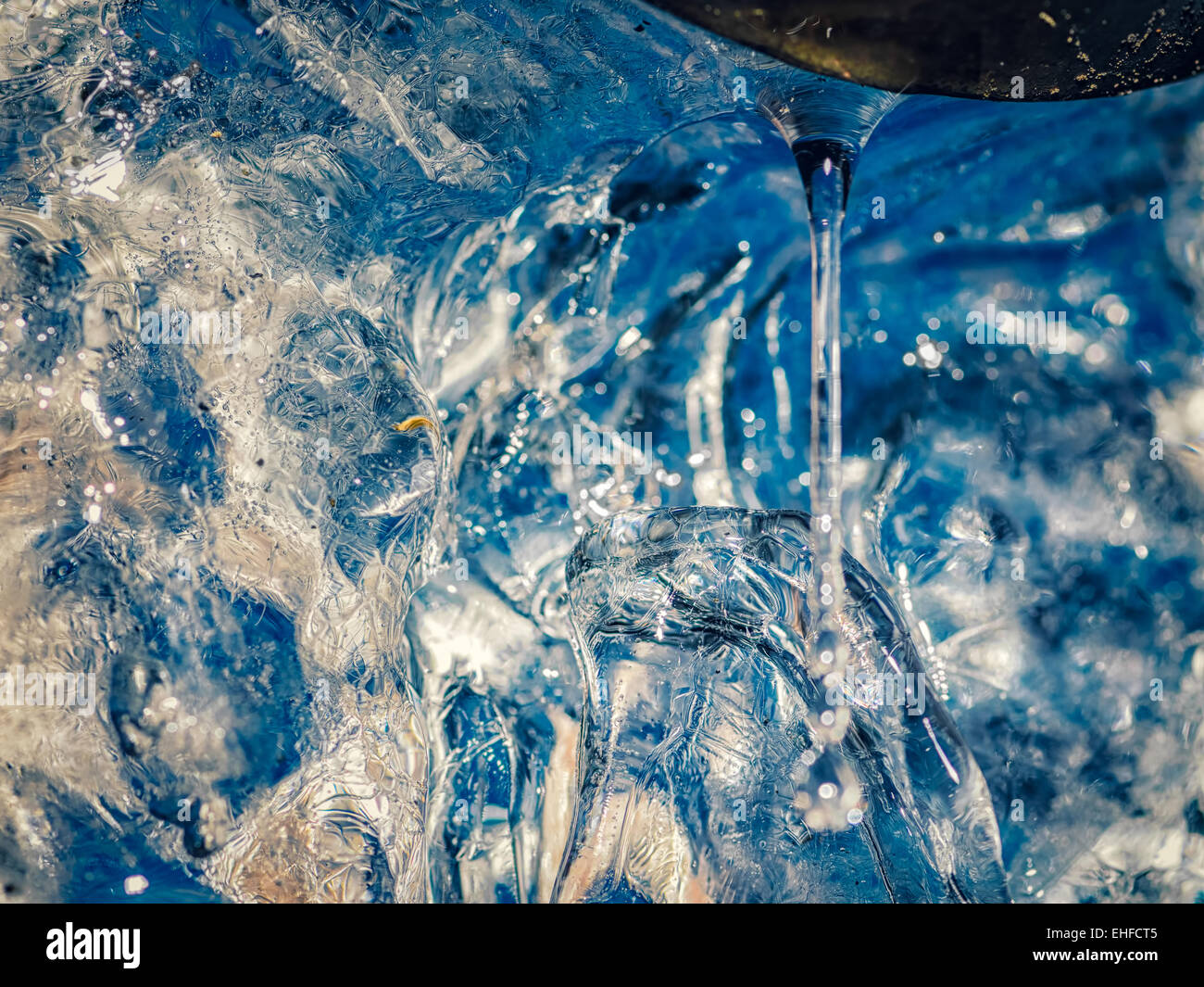 Goccia di ghiaccio fondente acqua al tubo di drenaggio, con il colore blu del cielo blu passando attraverso. Foto Stock