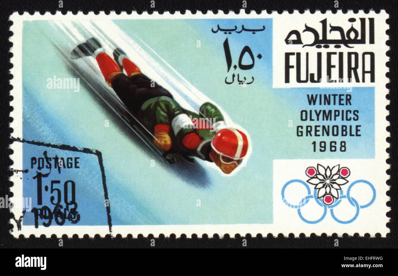 Francobollo da Fujeira mostra dei giochi olimpici invernali di Grenoble 1968. Discesa a slitta Foto Stock