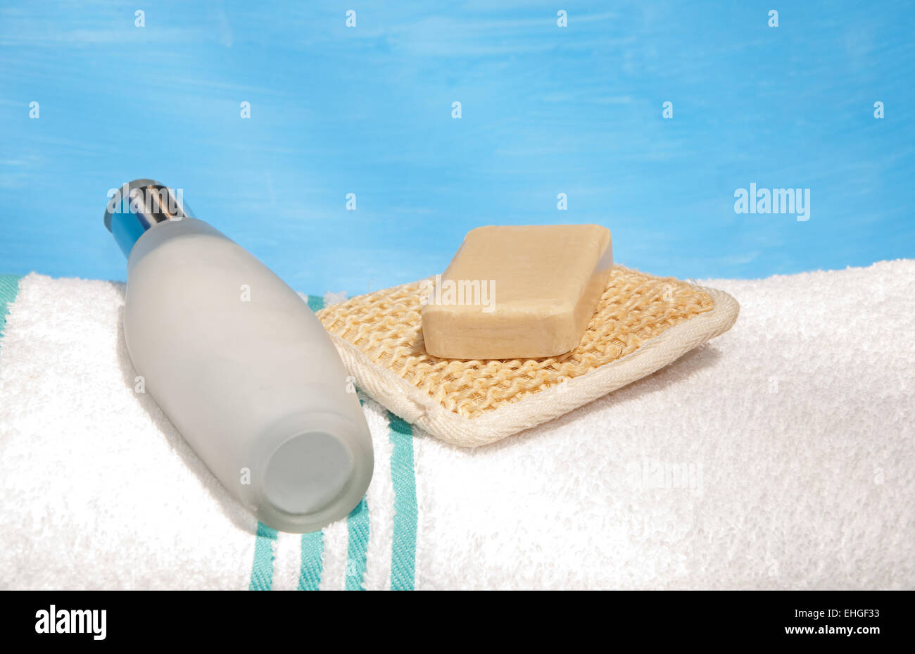 Lozione per il corpo, bottiglia di sapone e un peeling pad sulla parte superiore di un bianco asciugamano da bagno Foto Stock