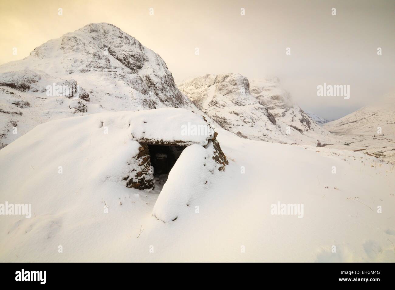 Ricovero di emergenza in Glencoe ,Highlands scozzesi con il "Te sorelle montagne sullo sfondo coperto di neve Foto Stock