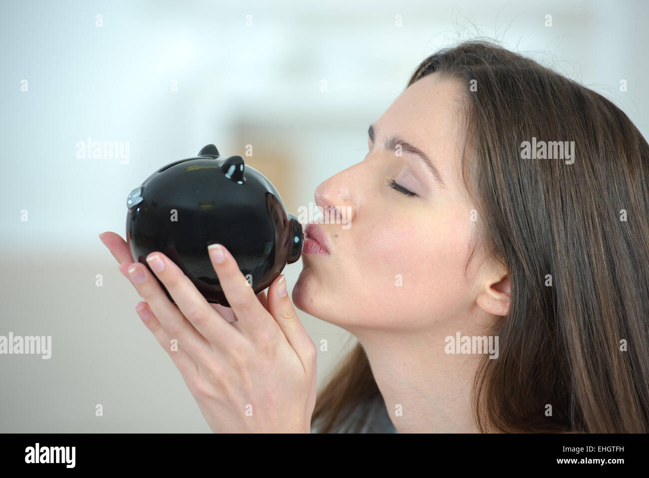 Donna mettendo moneta in un salvadanaio Foto Stock