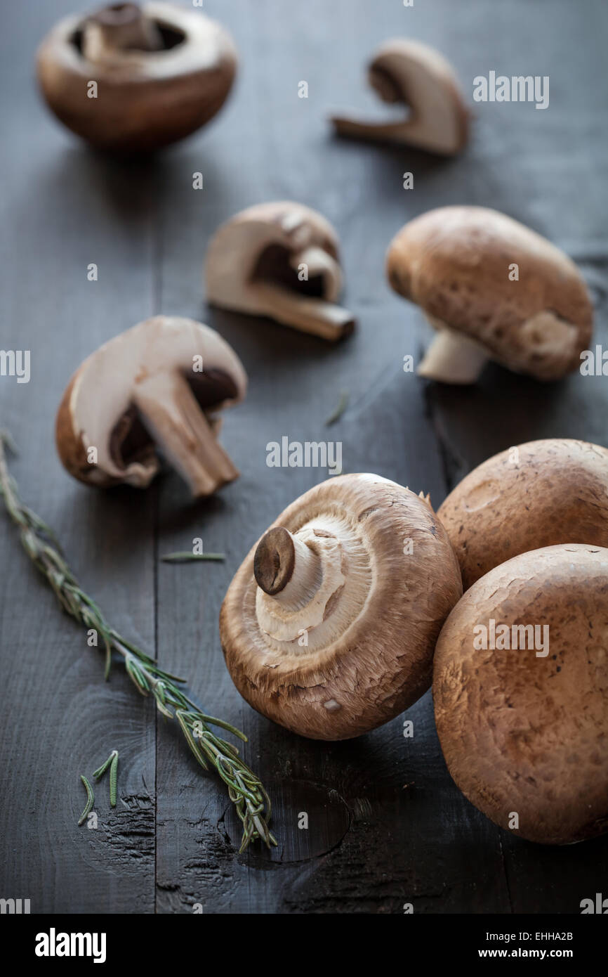 Fresh deliziosi funghi champignon rosmarino decorato su sfondo di legno Foto Stock