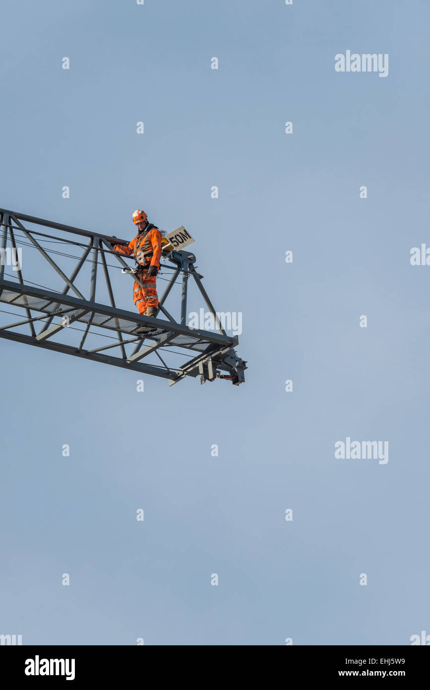 Un lavoratore edile sul braccio o braccio di lavoro di una gru su un sito in costruzione Foto Stock