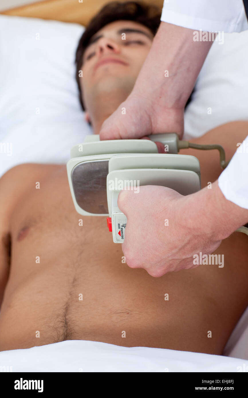 Un medico prepara una defibrillazione Foto Stock