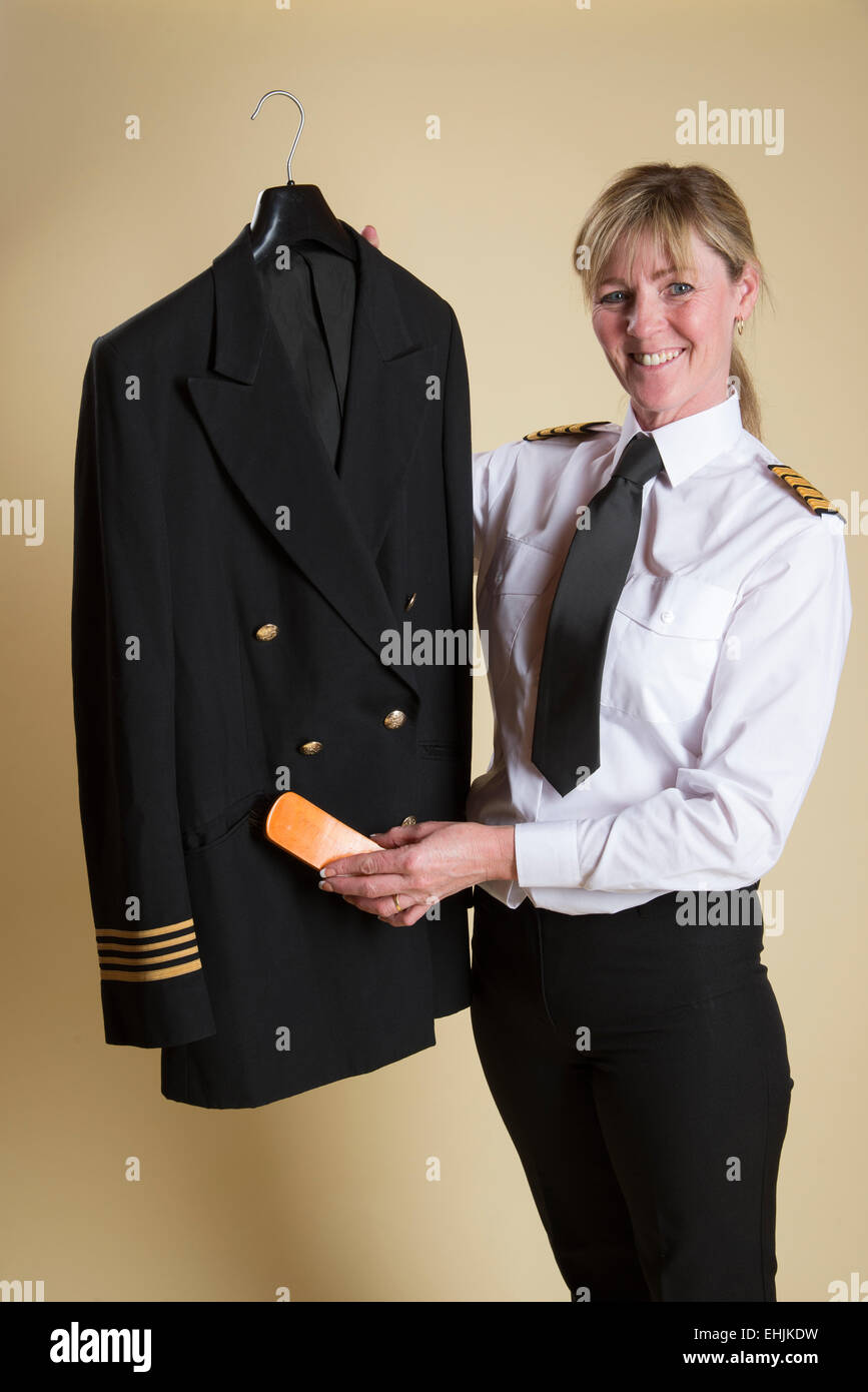 Compagnia aerea femmina capitano spazzolando la polvere dalla sua camicia uniforme Foto Stock