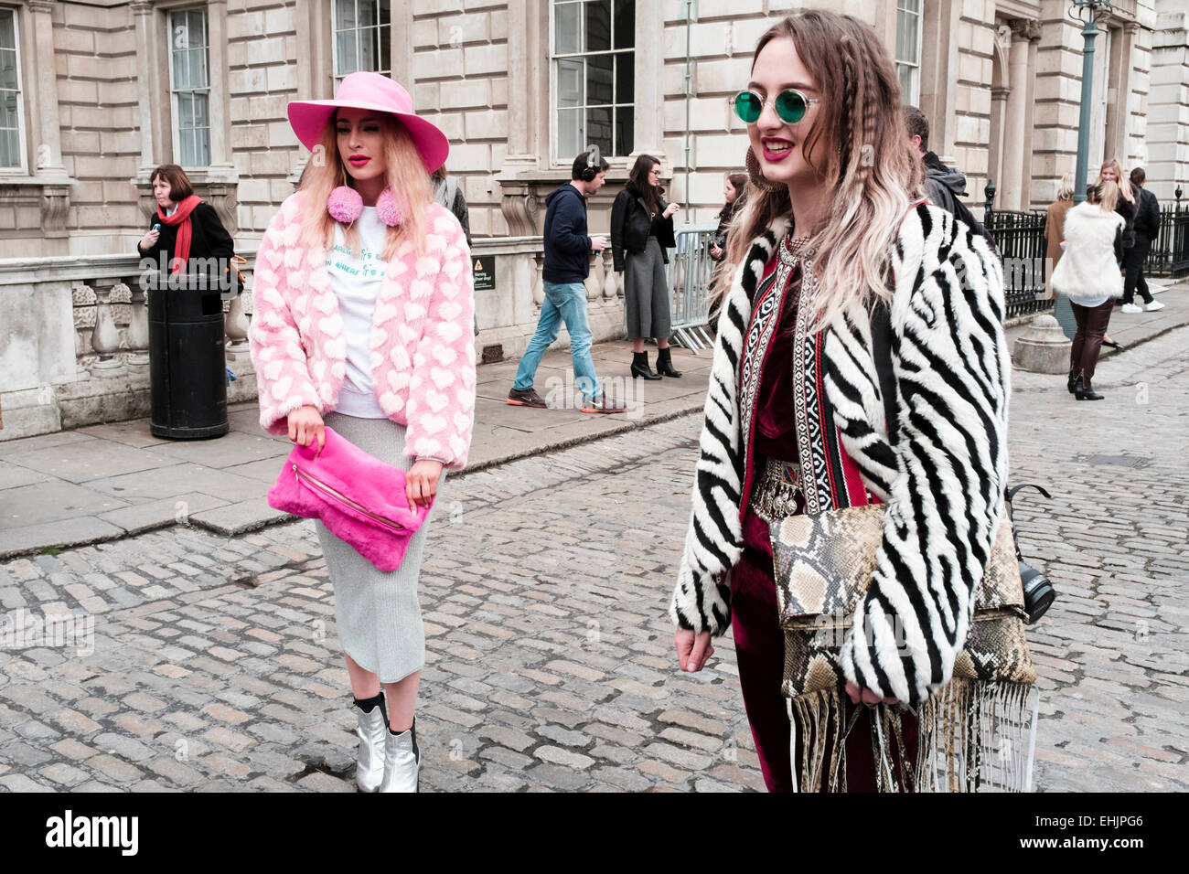 Vestiti alla moda giovani donne frequentano la London Fashion Week, febbraio 2015. Foto Stock