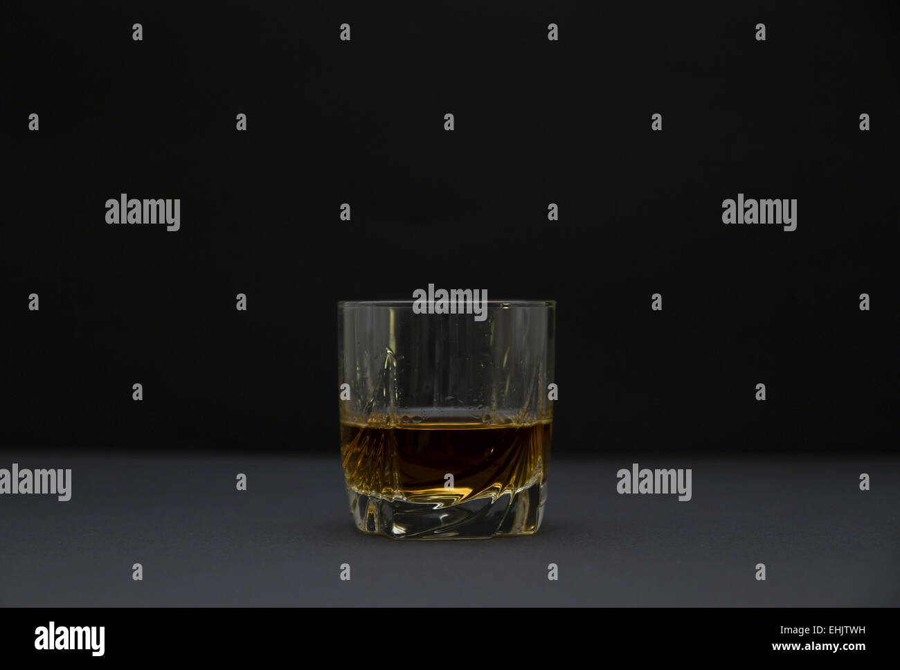 Vista laterale di un bicchiere di whiskey. Lo sfondo scuro e la profondità di campo. Foto Stock