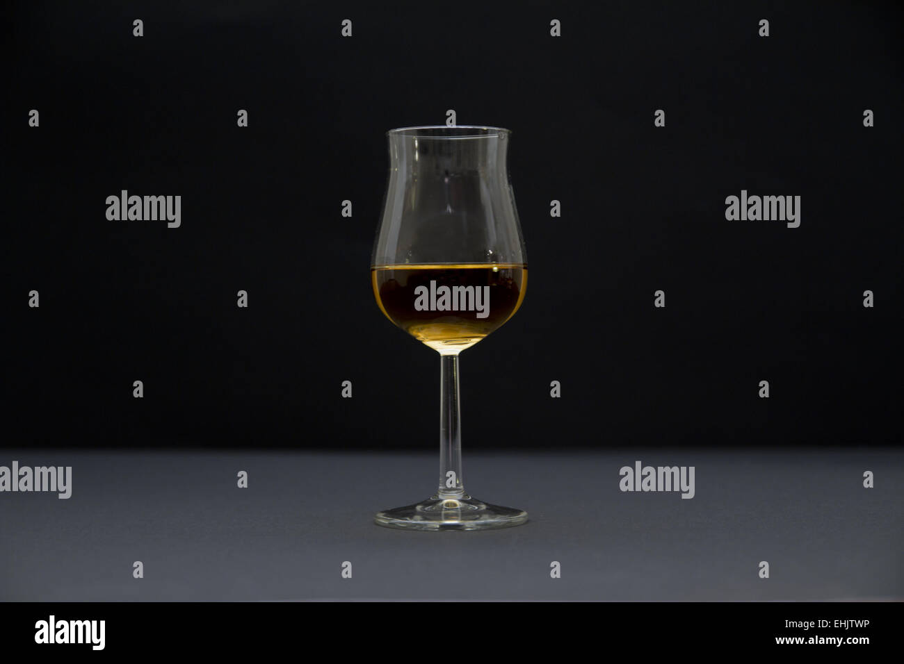 Vista laterale di un bicchiere di cognac. Lo sfondo scuro e la profondità di campo. Foto Stock