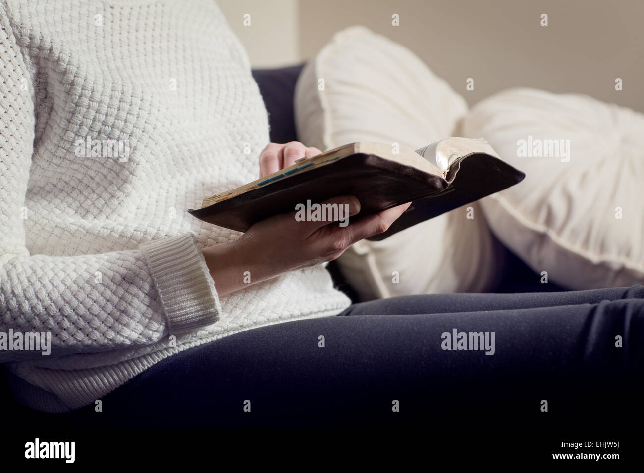 Close-up di una donna cristiana della lettura della Bibbia. Seduta in divano. Foto Stock