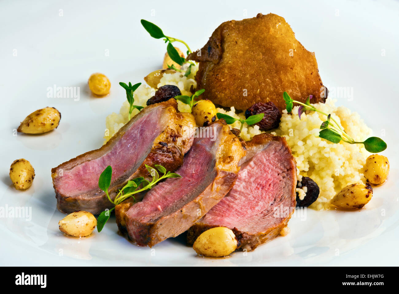 Grigliata di petto d'anatra servita con uva passa il couscous con il timo fresco e mandorle tostate Foto Stock