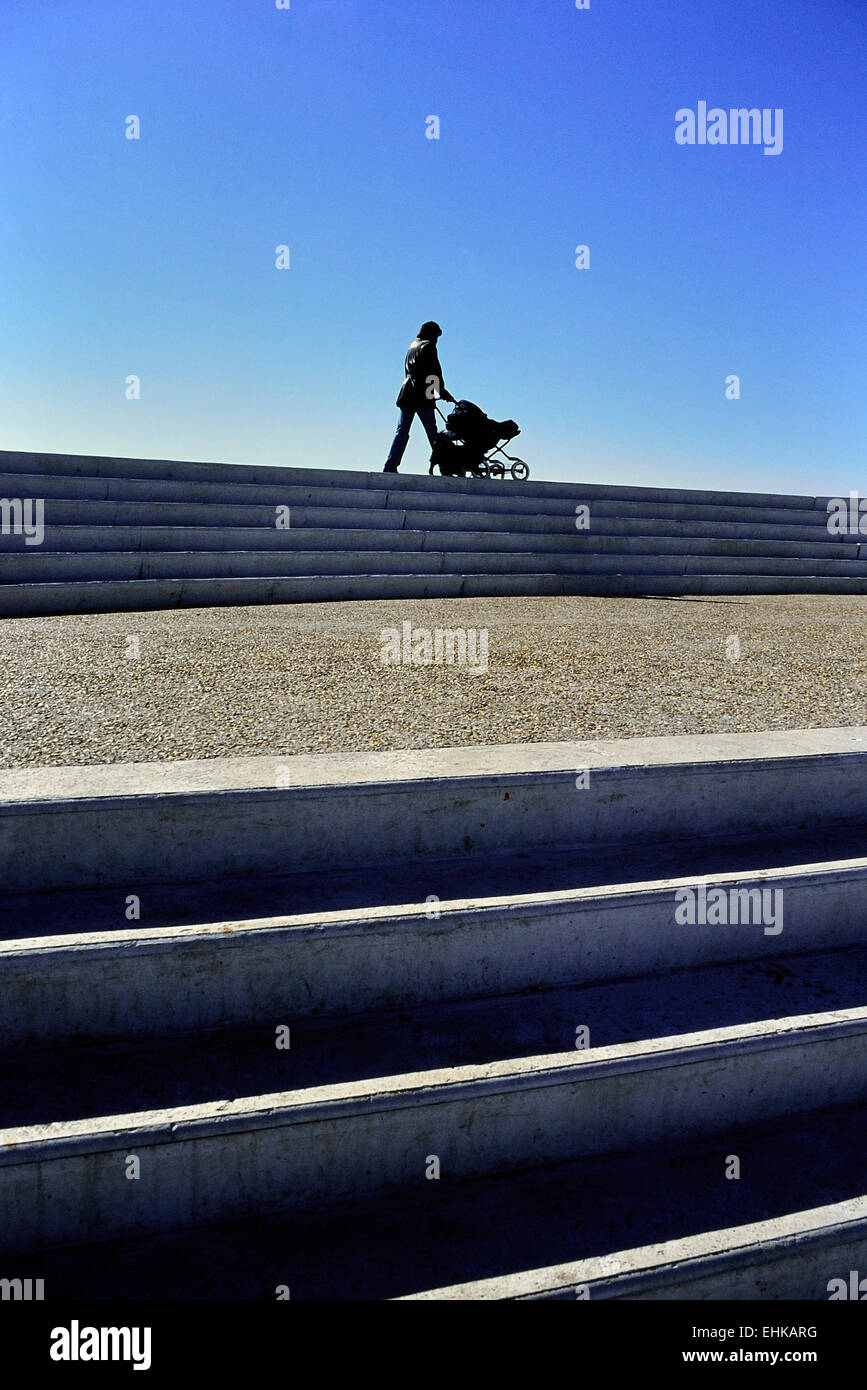 Madre spingendo il suo bambino in un passeggino Foto Stock
