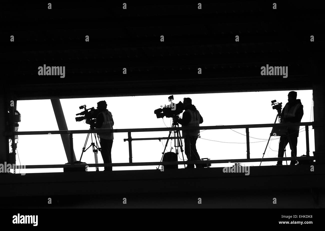 Cameraman televisiva catturare una partita sportiva alta su un gantry all'interno di uno stadio sportivo. Foto di James Mann Foto Stock