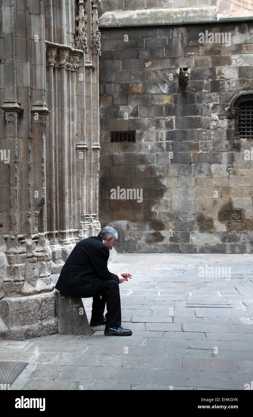 Uomo seduto da solo dietro la cattedrale nel quartiere Gotico di Barcellona e della Catalogna, Spagna Foto Stock