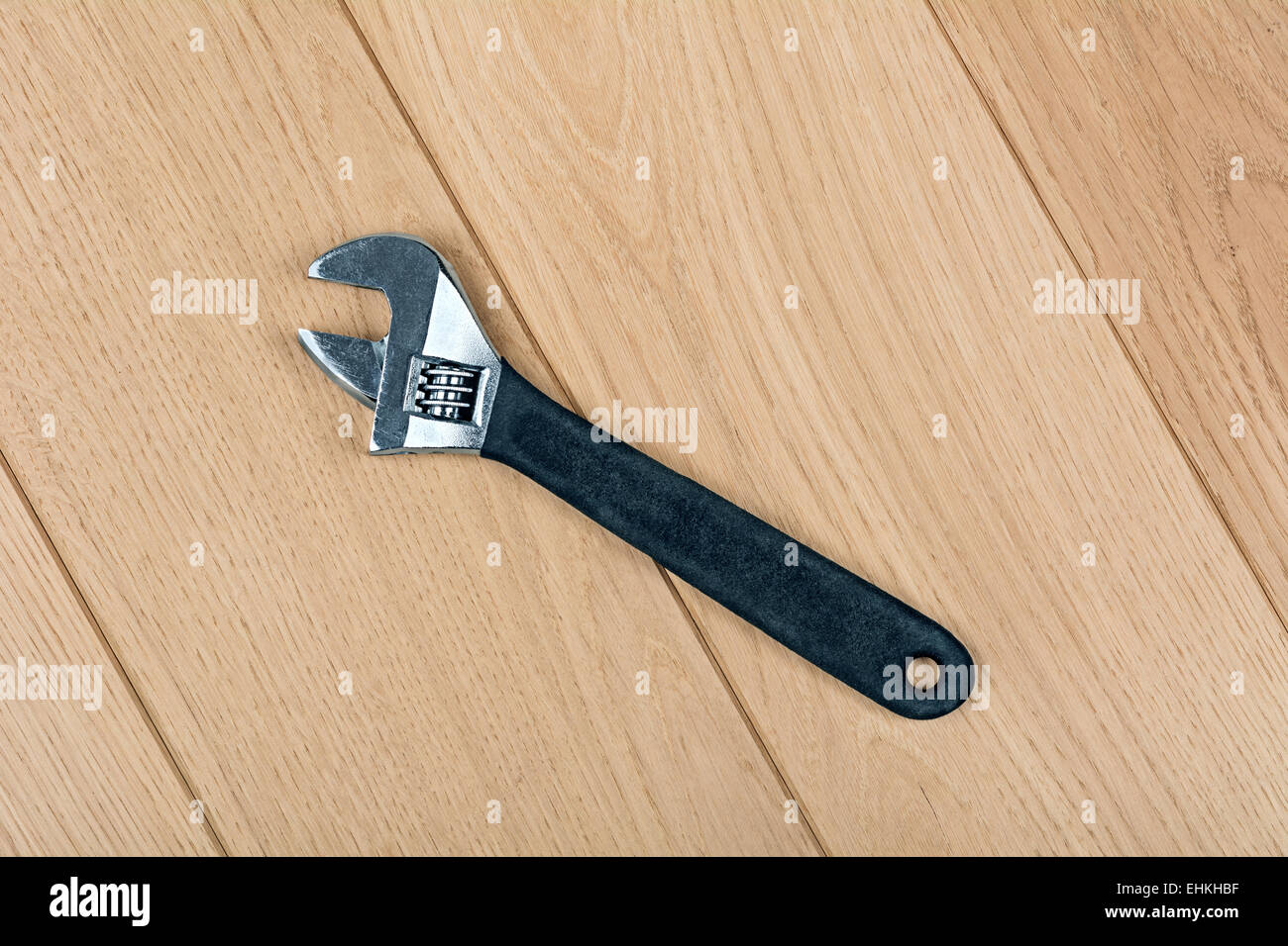 Chiave regolabile in rilievo sul pavimento in legno Foto Stock