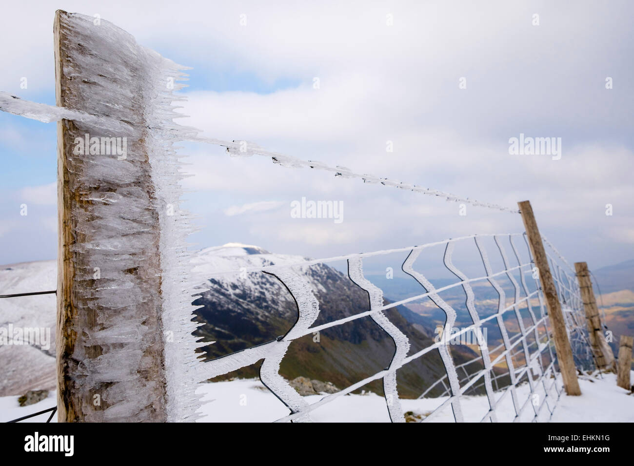 Battente di cristalli di ghiaccio congelato sul filo spinato e un palo da recinzione su Foel Goch mountain top nel tardo inverno. Parco Nazionale di Snowdonia, Galles del Nord, Regno Unito Foto Stock