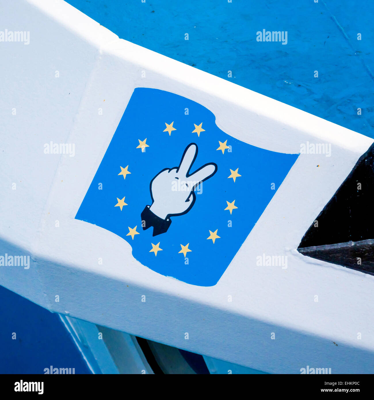 Bandiera europea con una mano che mostra maleducato "V-Segno" su un Regno Unito barca da pesca - critiche nei confronti della politica comune della pesca. Foto Stock