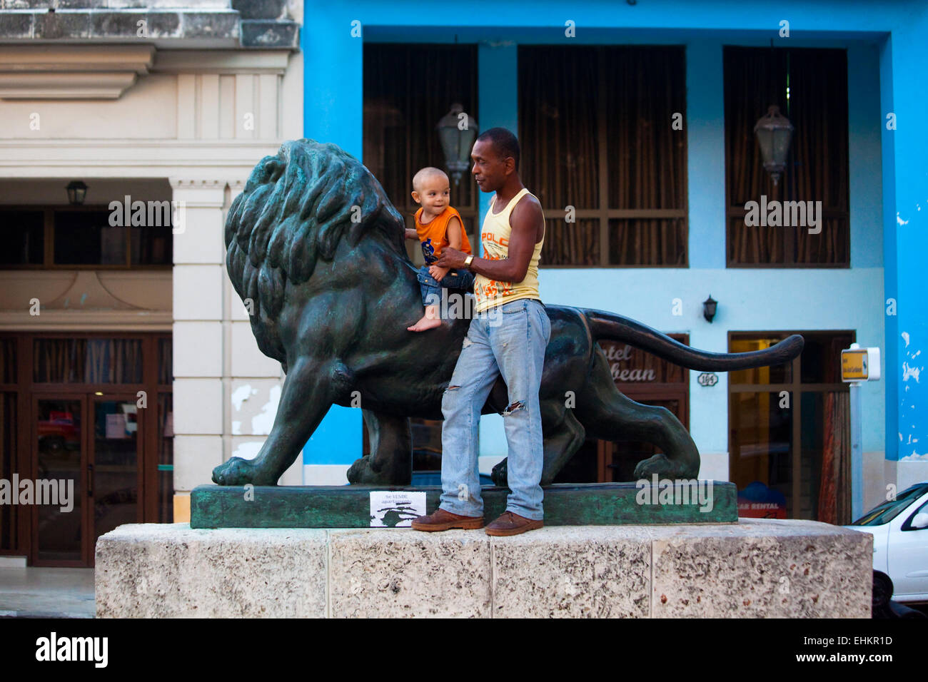Padre e figlio giocare su la statua del leone sul Prado, Havana, Cuba Foto Stock