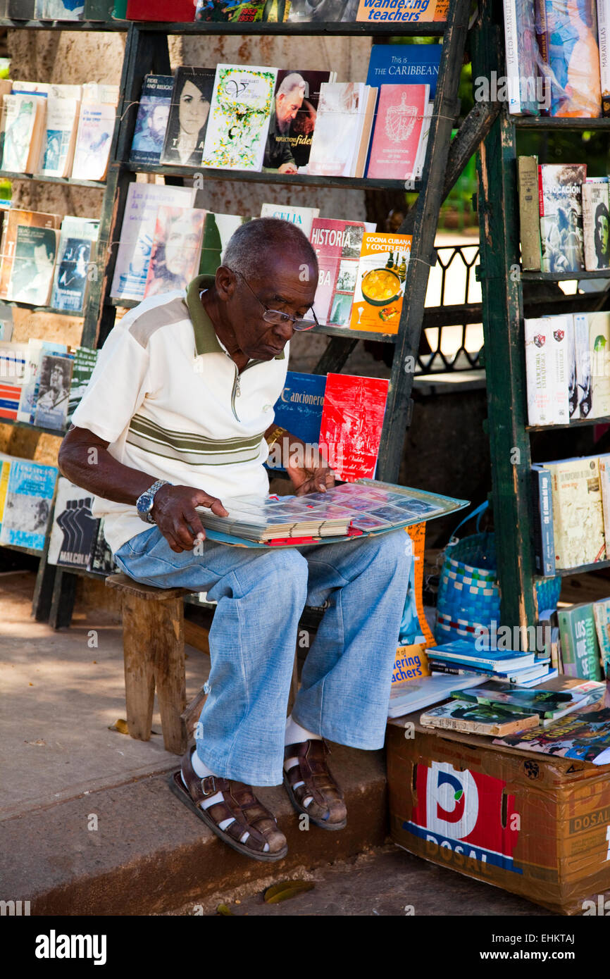 Un uomo esamina un libro in una strada del mercato di Plaza de Armas, Havana, Cuba Foto Stock