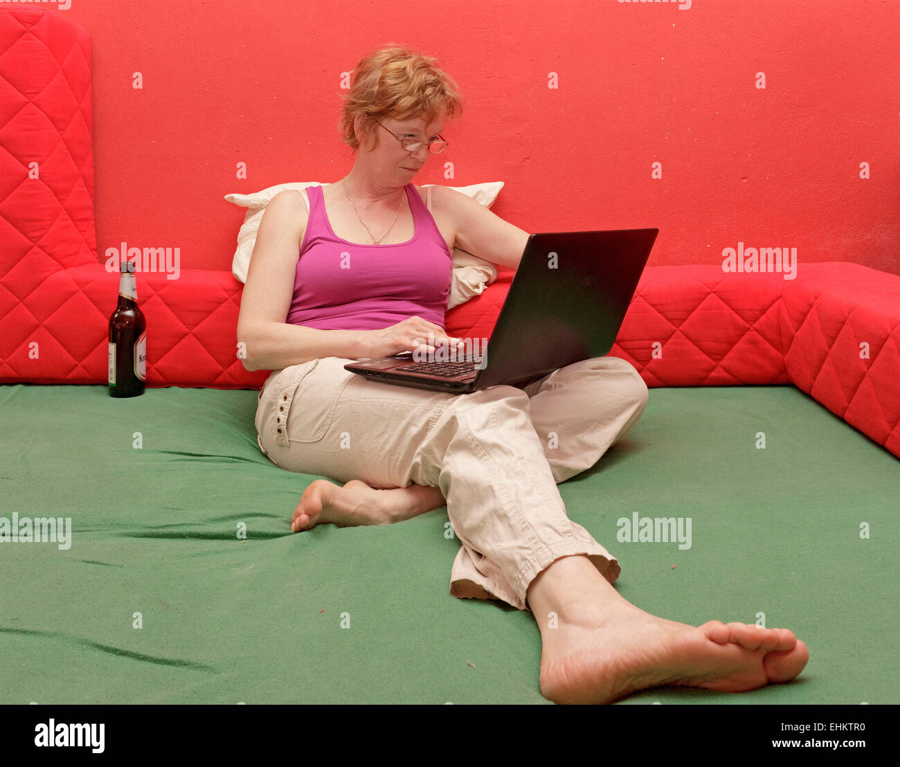 Donna con notebook seduta sul suo letto Foto Stock