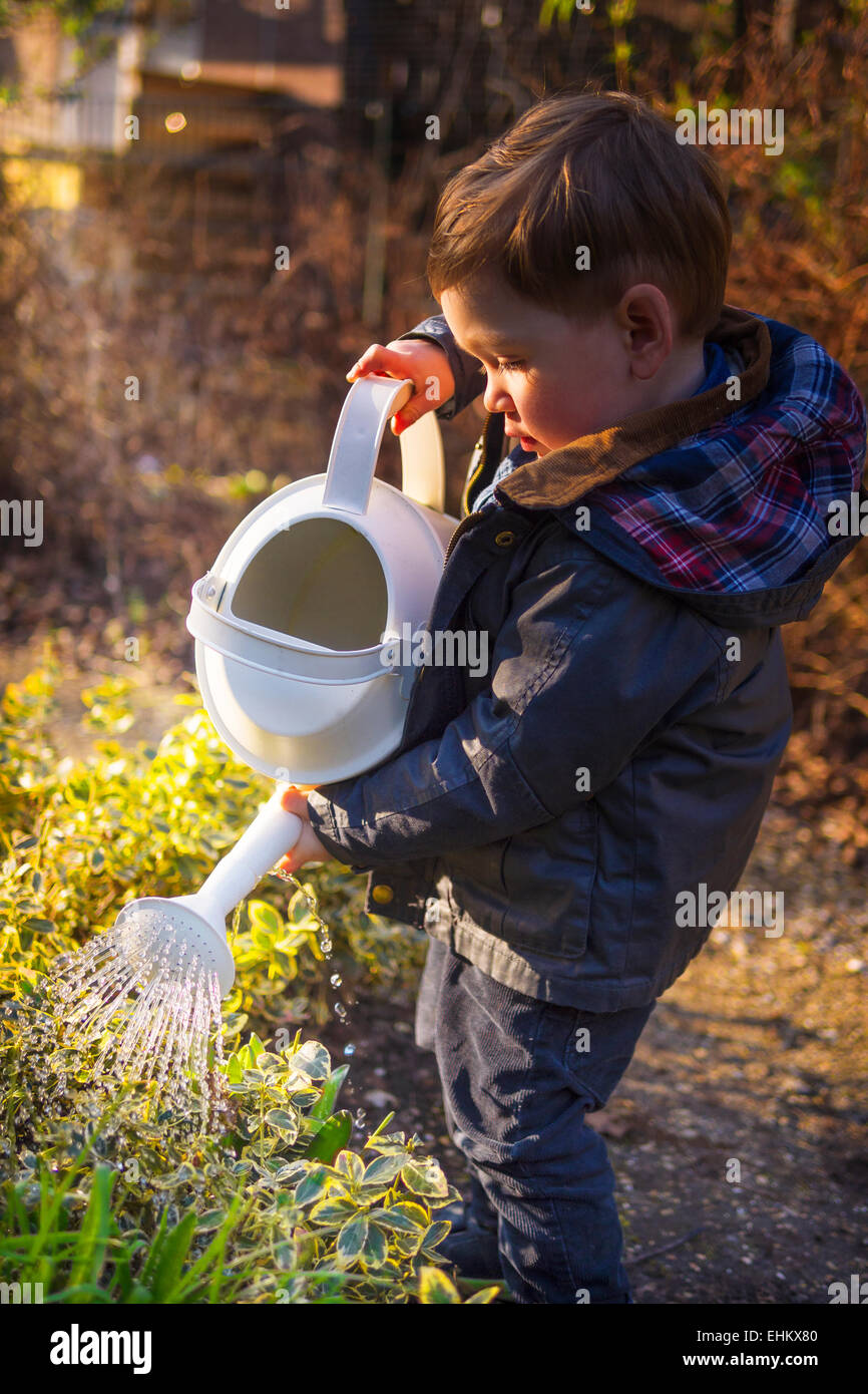 Carino piccolo ragazzo di impianti di irrigazione in giardino Foto Stock